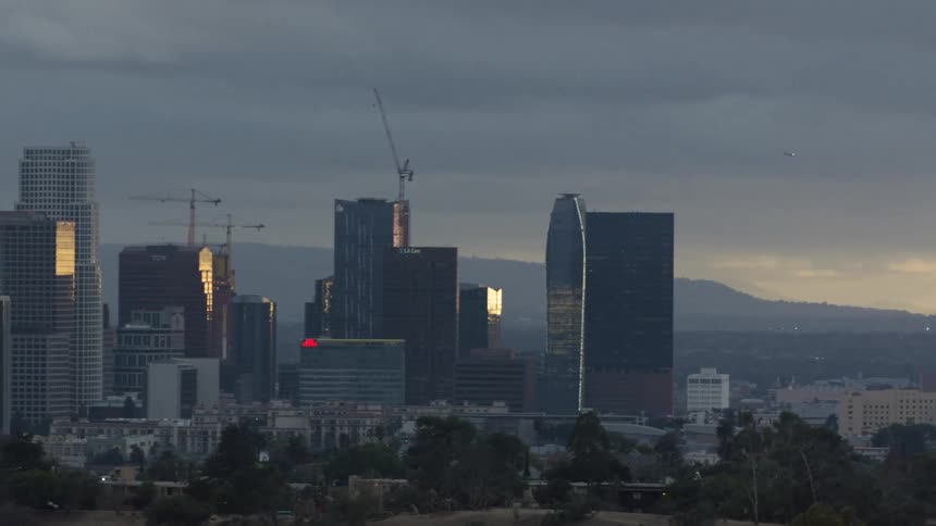 Construction cranes work on skyscrapers in downtown on misty day