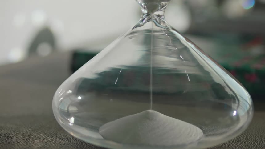 Sand falls to the bottom of an hourglass