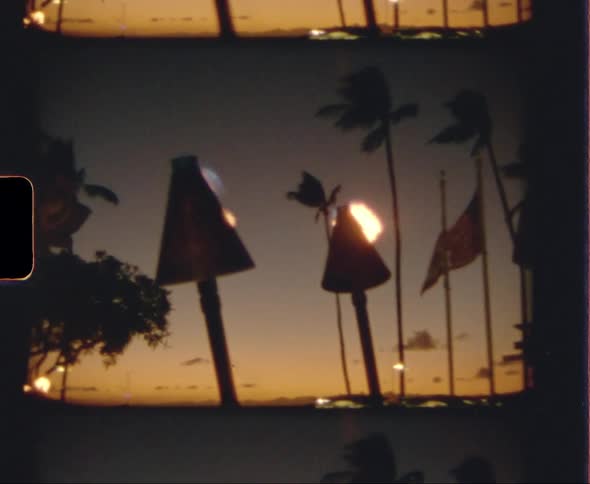 Tiki torches burning in a tropical area at sunset