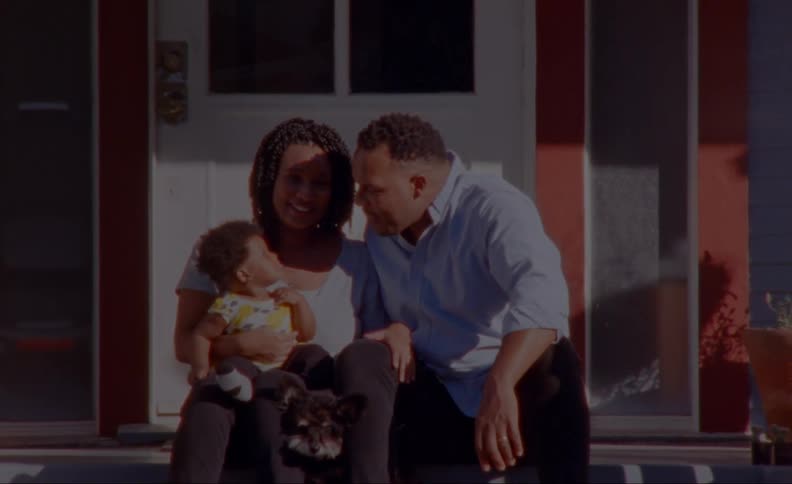 A baby touches his fathers face as the family poses on their front porch