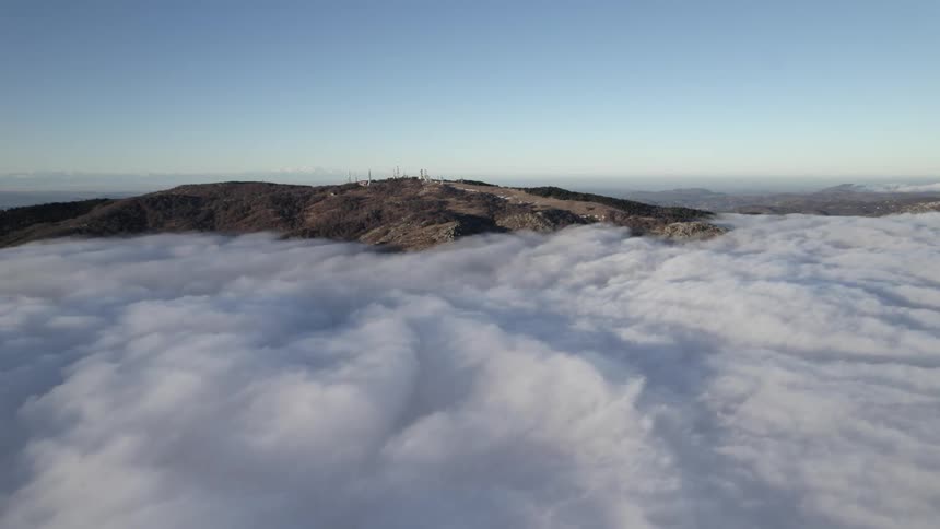 Complex on mountain top show above low lying clouds a mist covers town in the background