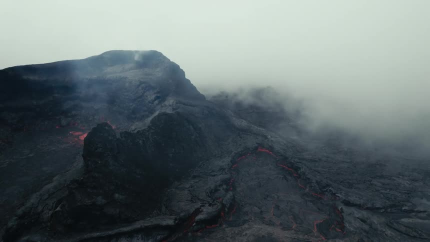 An aerial view of lava flowing from an erupting volcano