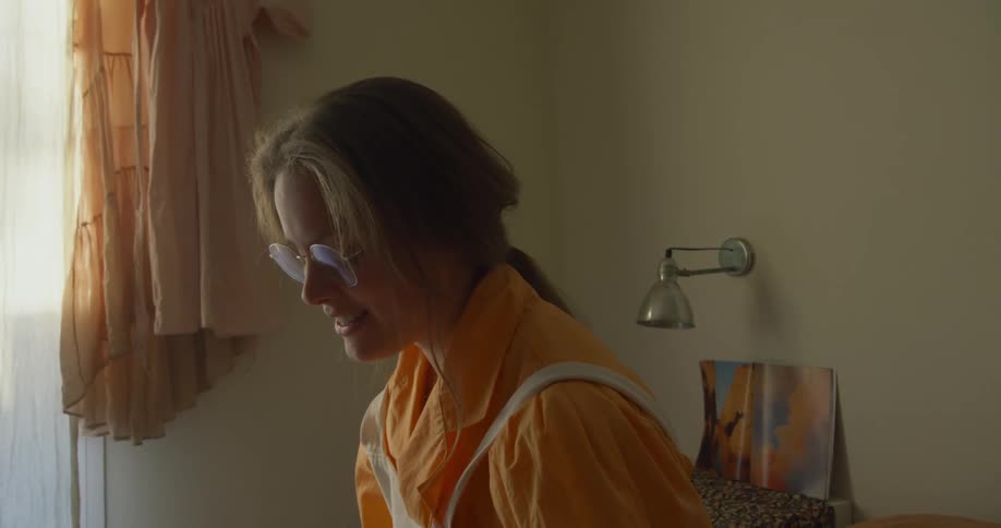 Friends smile and talk in room near window with wall mounted lamp in background