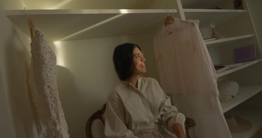 A woman sits and talks in the closet