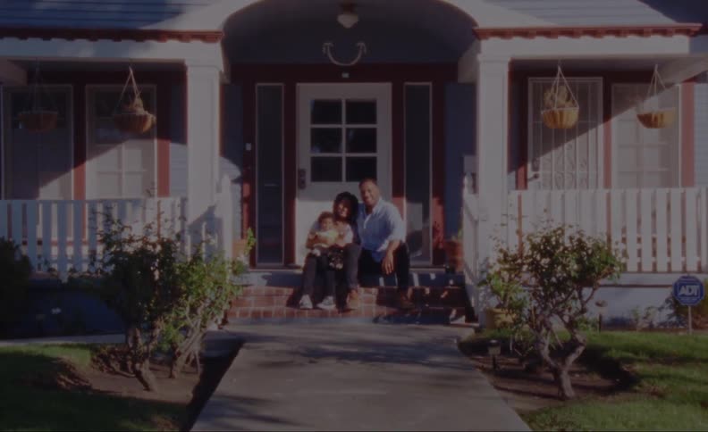 Family sits on cottage porch steps with dog