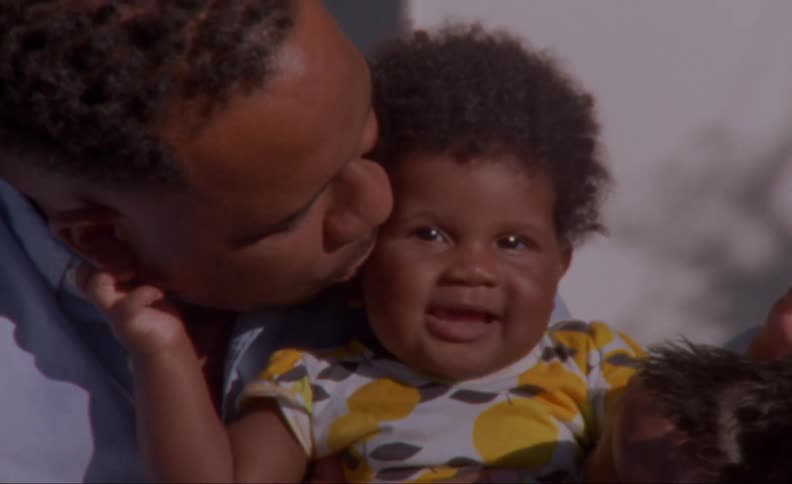 Man holds and kiss smiling child as dog sits nearby