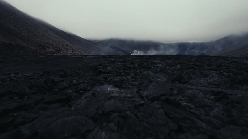 An aerial view of an empty field and mountains in the distance on a foggy day