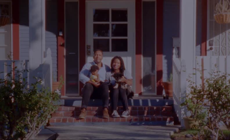 A family poses with their dog on the front porch