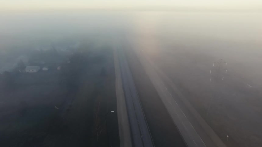 Aerial view through the fog of cars traveling on an open road