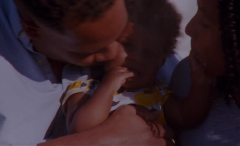 Father leans down and kisses child as the toddler touches his mother