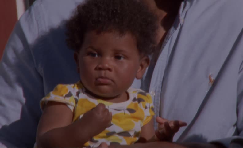 Father holds child as he sits outdoors talking with another adult