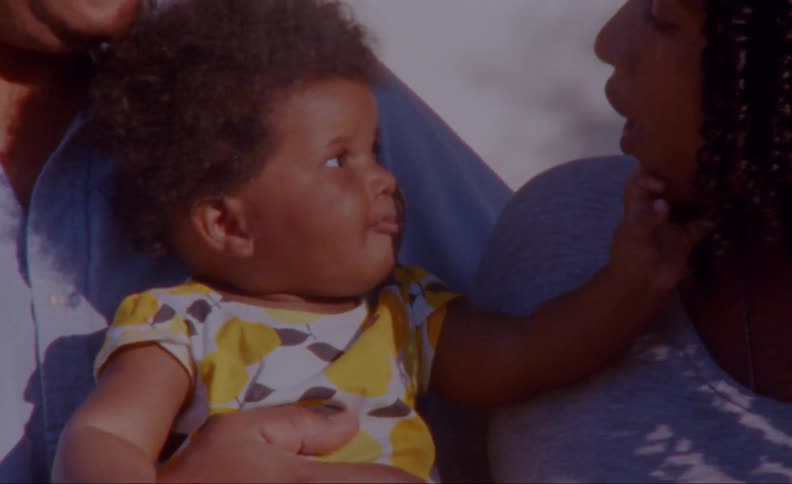 Father holds toddler as child reaches form mothers mouth as she speaks