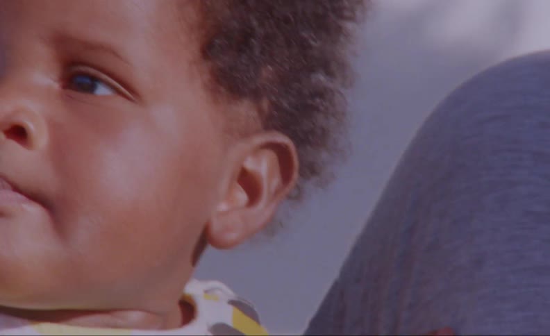 Mom talks to and caresses her baby boy while they sit outside in the sunshine