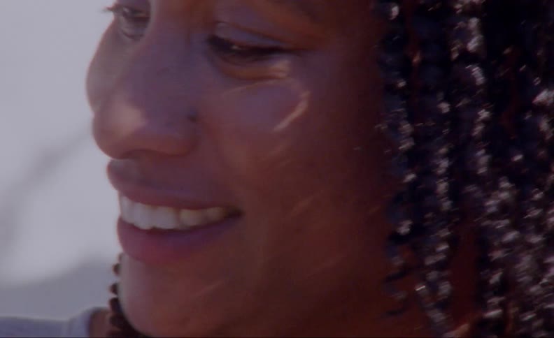 A woman is smiling outdoors during the daytime
