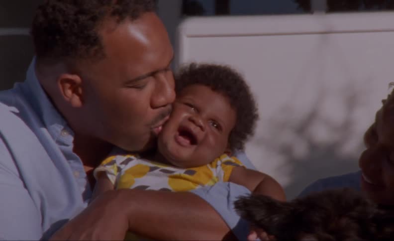 Mother smiles and watches husband kiss their baby
