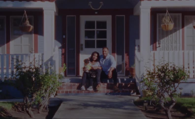 A family poses for a photograph sitting on the front steps with baby and puppy