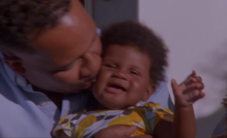 Father kiss laughing child as dog sits nearby