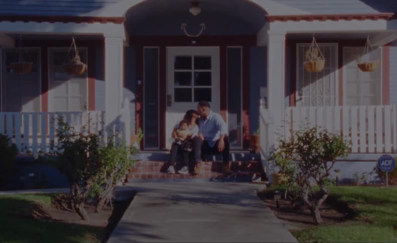 A family is sitting together outside of their home