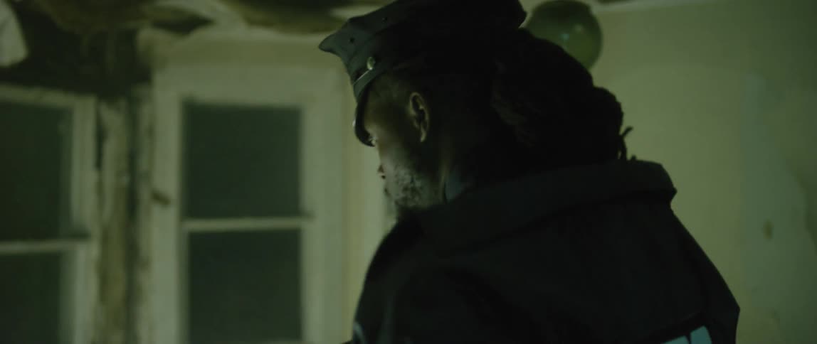 A cop shines his flashlight in a destroyed home