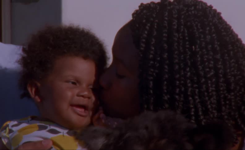 Sister kisses laughing toddler as dog sits nearby