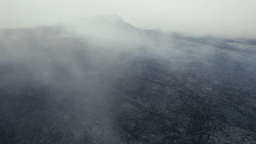 Layers of fog billow over dark rock slopes