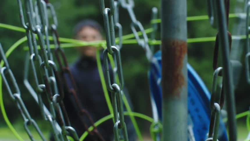 Child aims and throws blue disc into basket made from chains