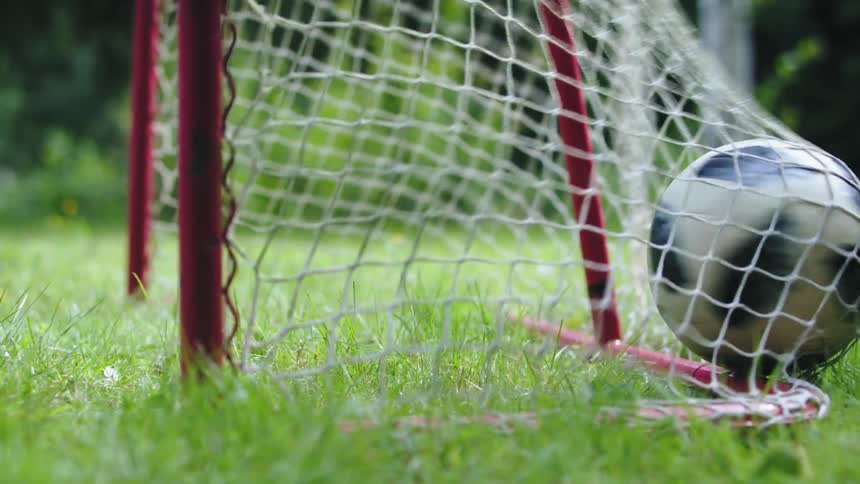 A soccer ball goes into the goal and hits the net