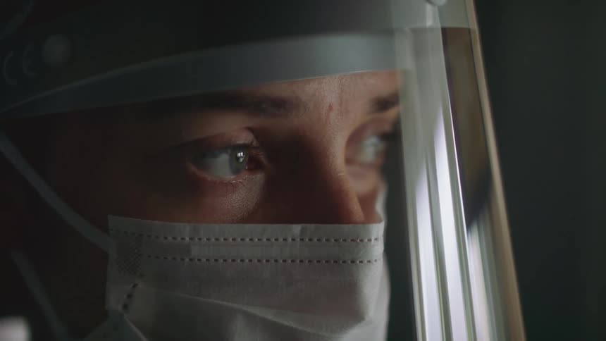A woman wearing a face mask and shield looking anxious and apprehensive