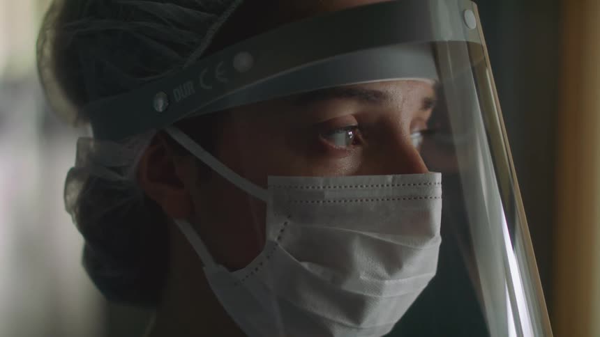 A nurse looks out the window of a hospital