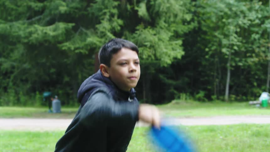 A boy is playing frisbee outdoors in spring