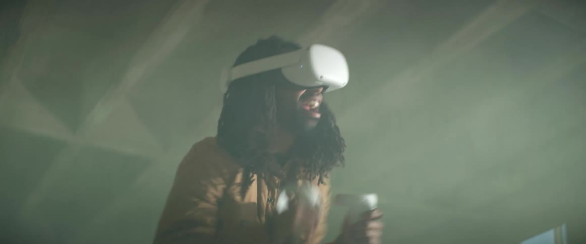 A man is standing indoors and playing virtual reality
