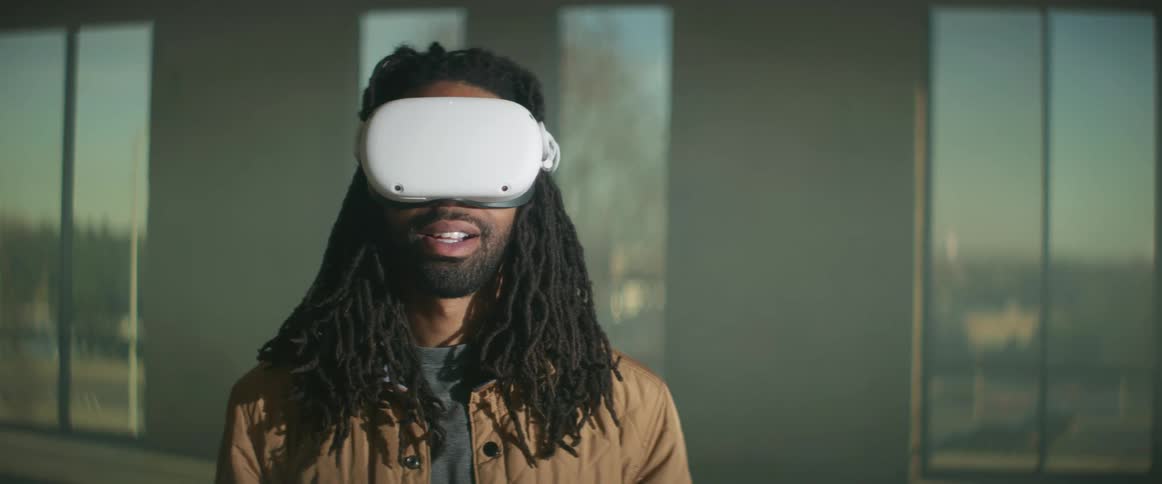 A man puts on a virtual reality headset as cars drive by outside