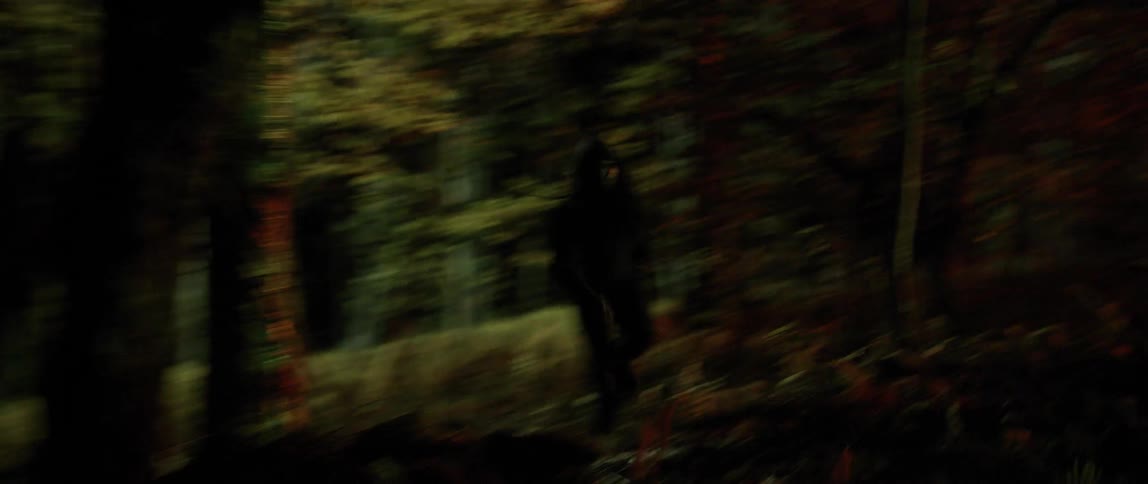 A man runs fast through a forest with spotlights pointing in