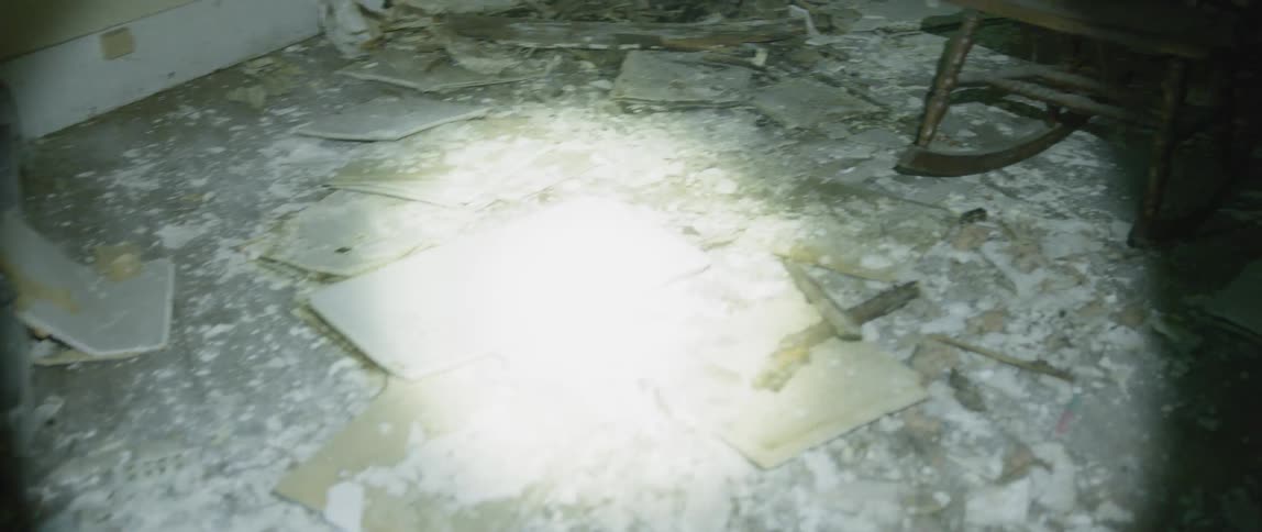 Someone shines a flashlight in an abandoned home