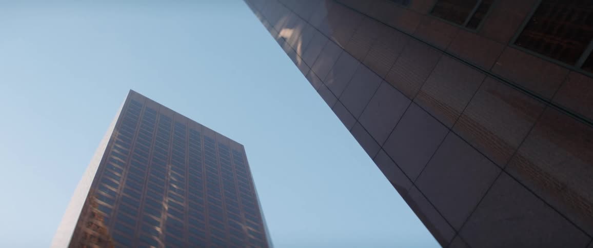 Skyscraper facades reflect the surrounding buildings against a blue sky