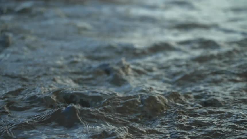 Water ripples and shines in the light as it moves over rocks