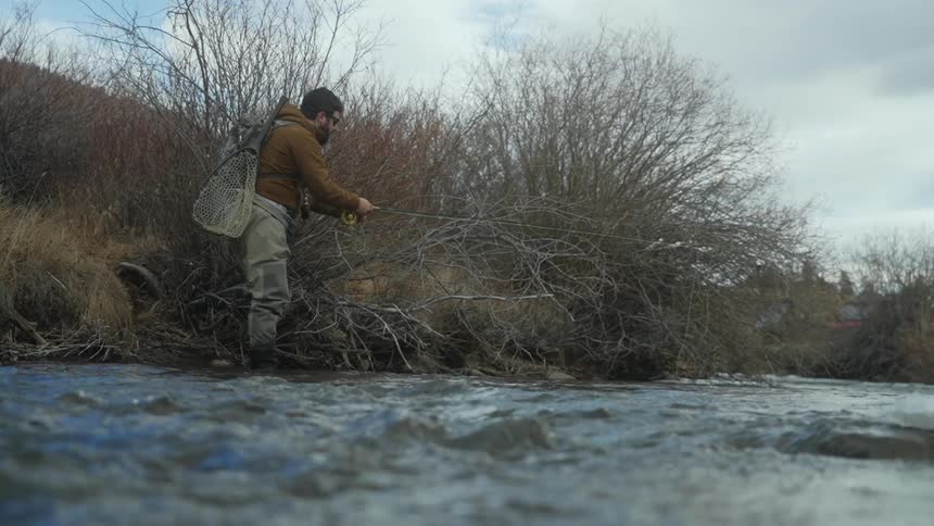 A man stands in a river and fishes