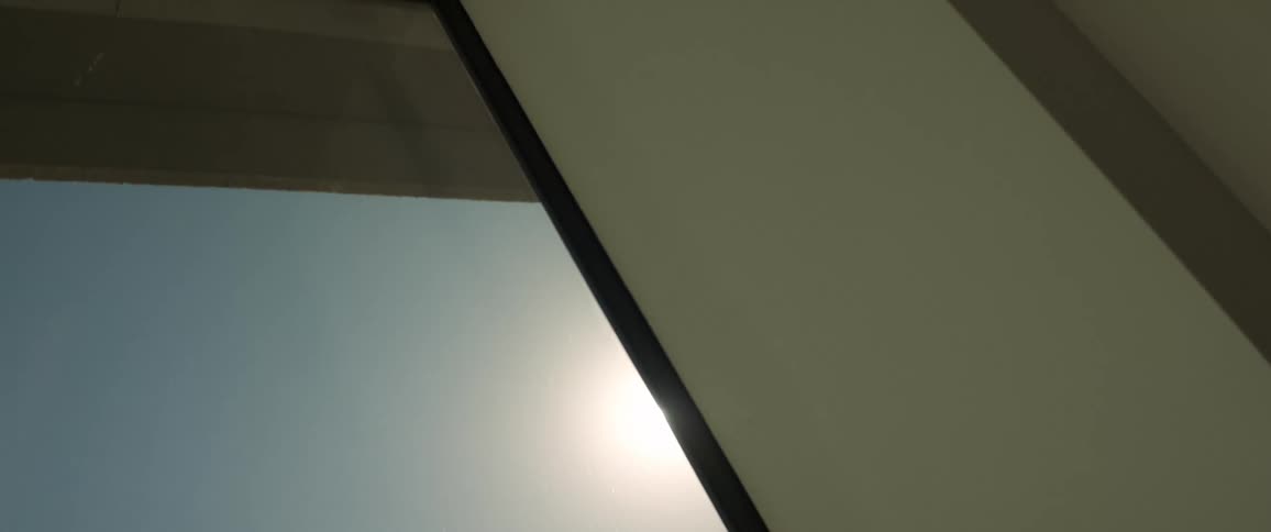 The sun peaks on the side of the building