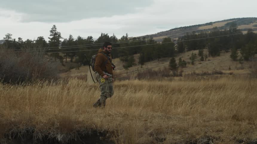A man is hiking with his fishing gear