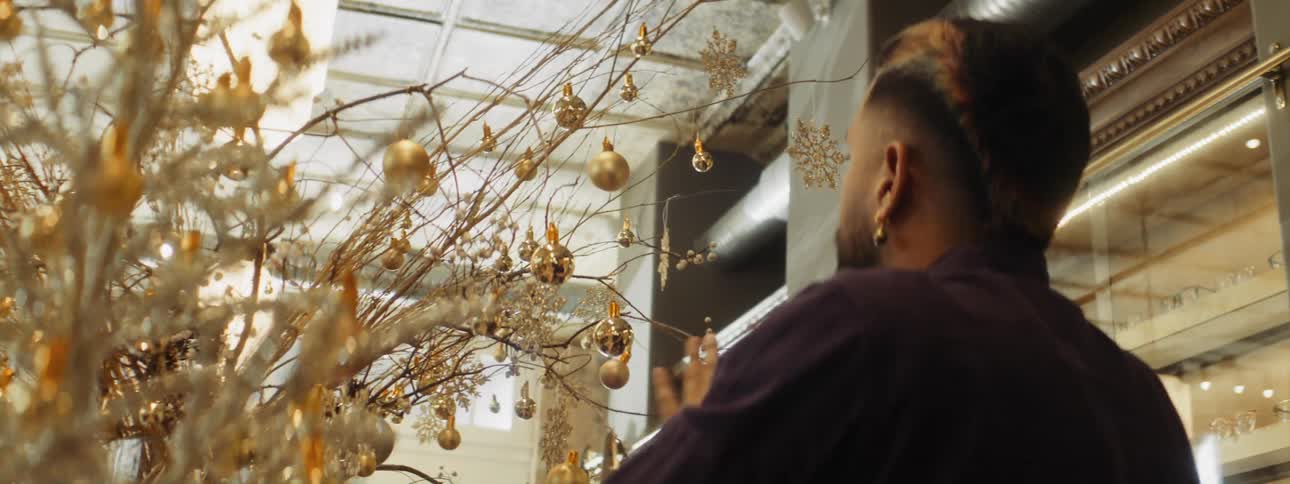 Store employee decorates store with golden christmas ornaments