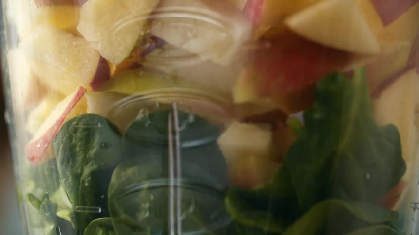 Apples being added to spinach in a blender