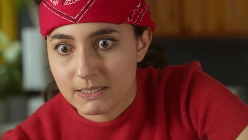 A young woman with a red bandana wrapped around her forehead making funny faces