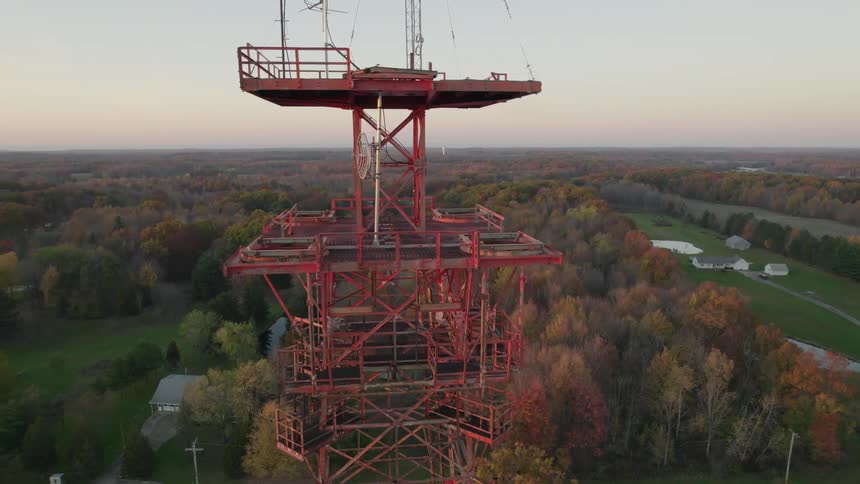 A tall metal tour is by the forest