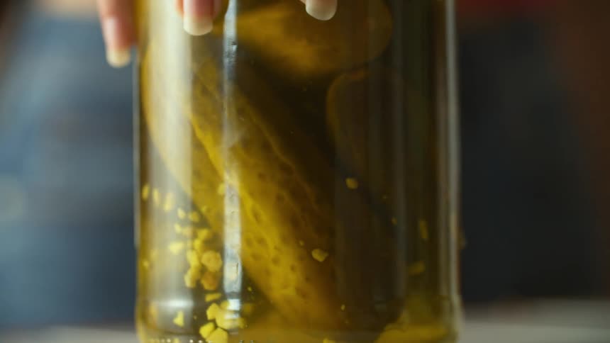 A person puts a jar of pickles on the counter