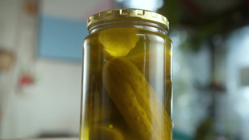 A jar of pickles is sitting on a kitchen counter