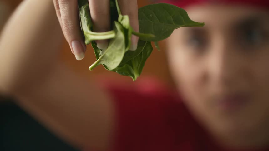 A girl has a handful of leaves and she is slowly dropping them