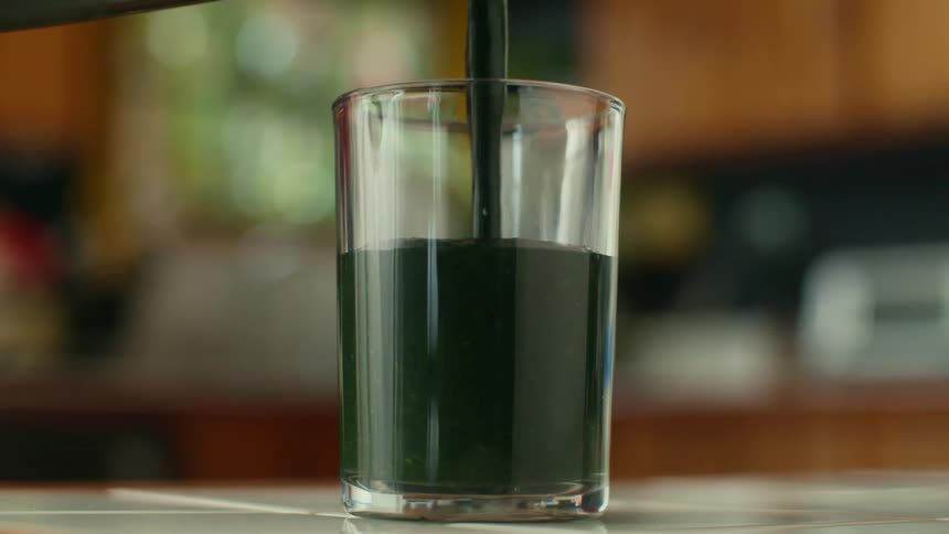 A smoothie is being poured in to a glass in a house