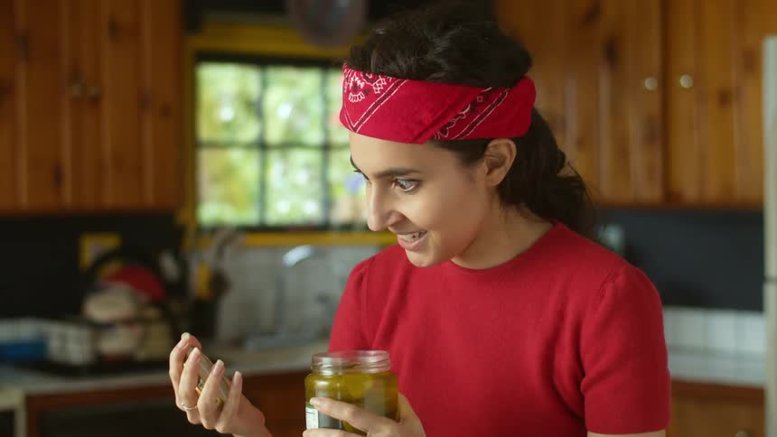 A woman opening a pickle jar and reacting excitedly