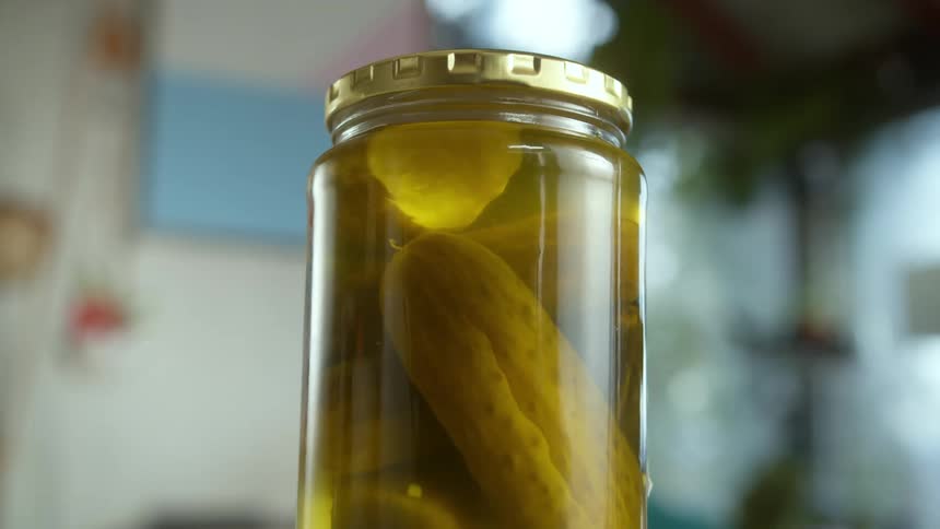 A jar of pickles is sitting on a kitchen counter
