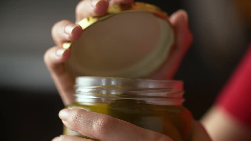 Women removes lid from pickle jar